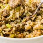 Bowl of dirty rice with green onions on top.