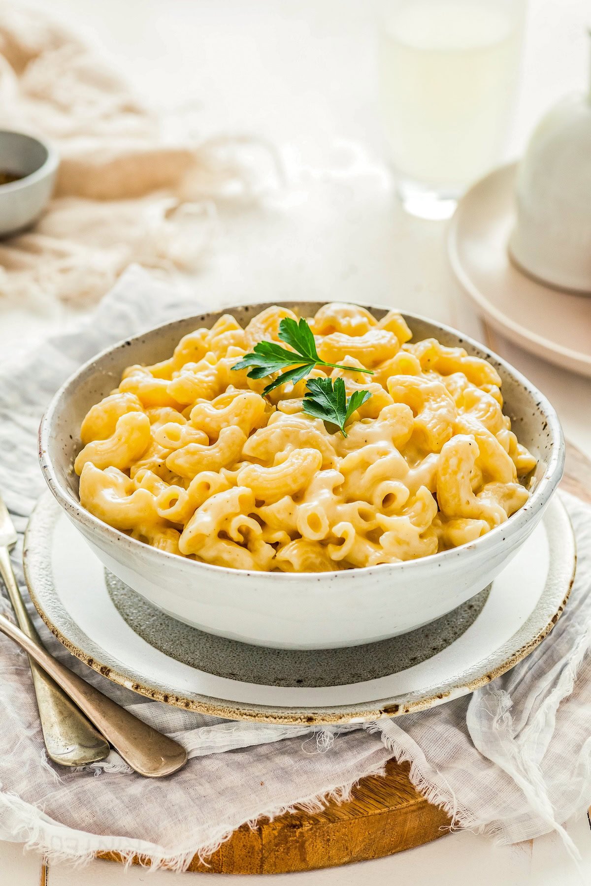 A small white bowl is filled with creamy, rich macaroni and cheese. It's garnished with fresh herbs. 