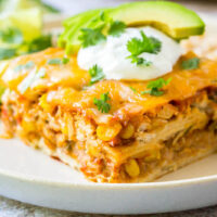 Mexican casserole topped with sour cream and cilantro and served on a plate.