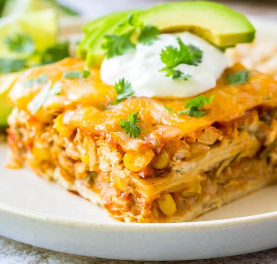 Mexican casserole topped with sour cream and cilantro and served on a plate.
