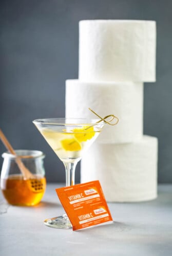 Quarantini in a glass with toilet paper and vitamin c.