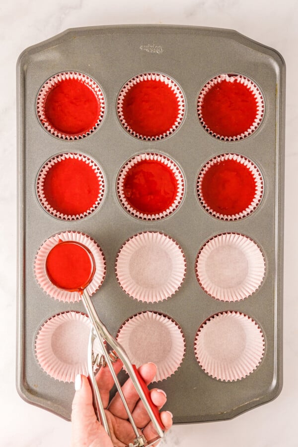A cupcake tin being filled with batter.