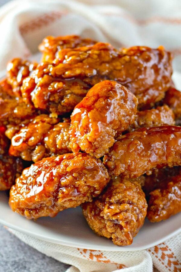 Sweet and spicy sticky chicken tenders on a plate.