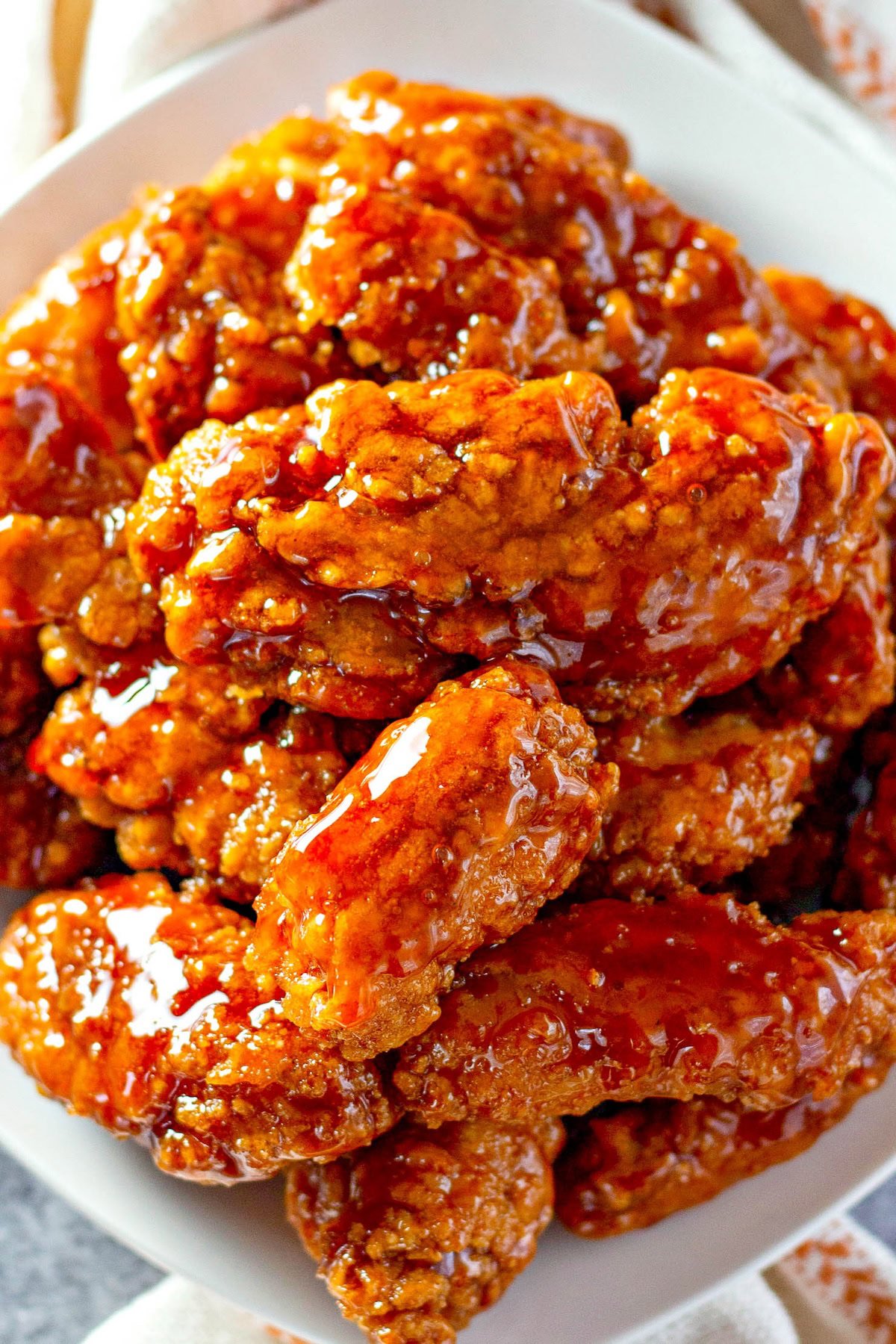 Crispy chicken tenders are coated in vibrant sticky sauce. 