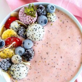 A strawberry smoothie bowl with mixed berry and fruit toppings.