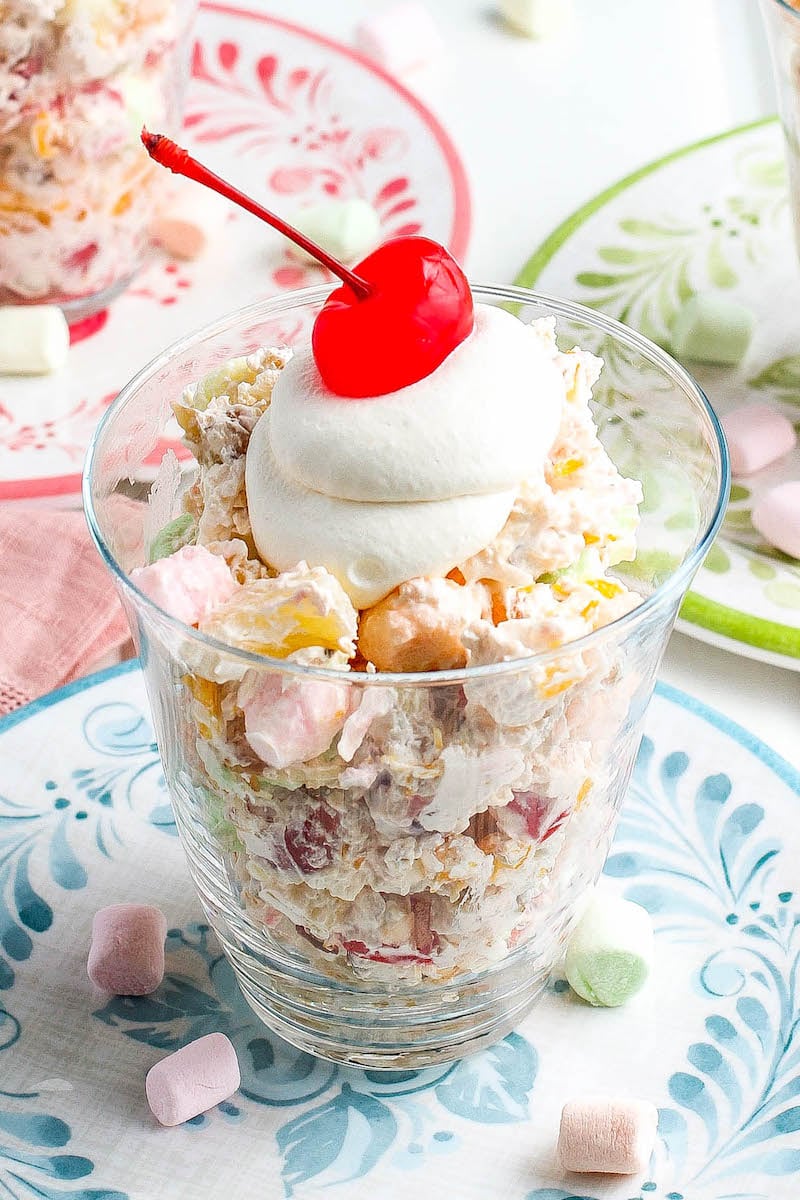 Ambrosia salad served and topped with more whipped topping and a cherry.