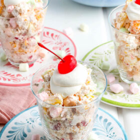 Ambrosia salad served and topped with more whipped topping and a cherry.