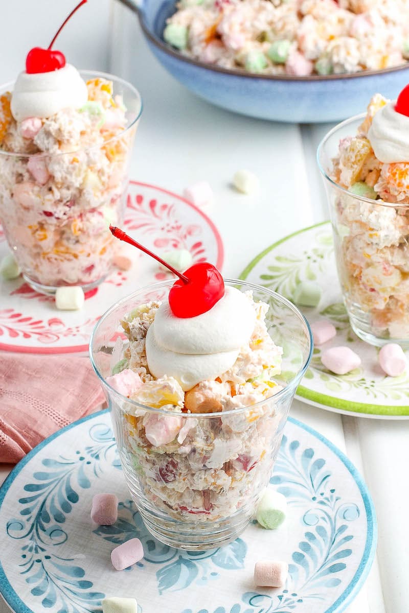 Ambrosia salad served and topped with more whipped topping and a cherry.