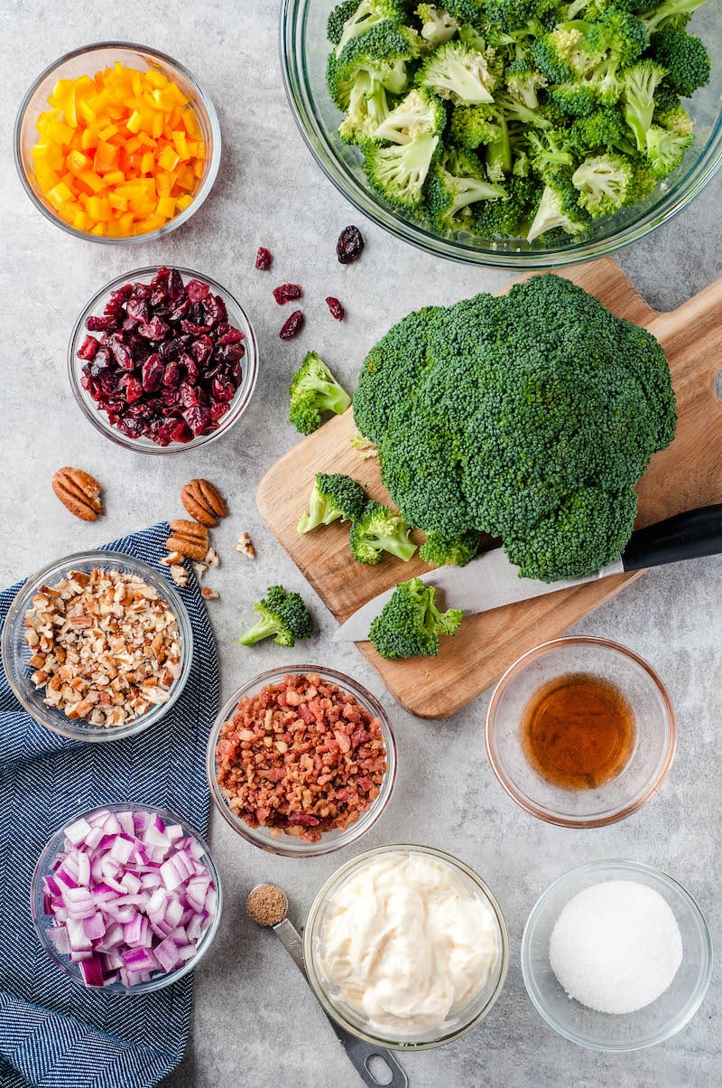 Ingredients in bowls and broccoli on a cutting board. 