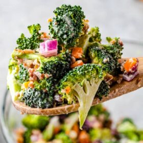 Prepared broccoli salad being spooned into a bowl.