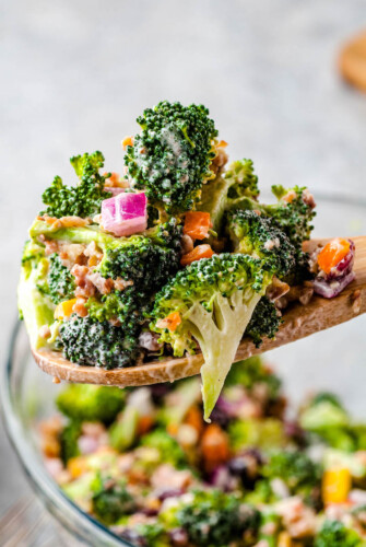 Prepared broccoli salad being spooned into a bowl.
