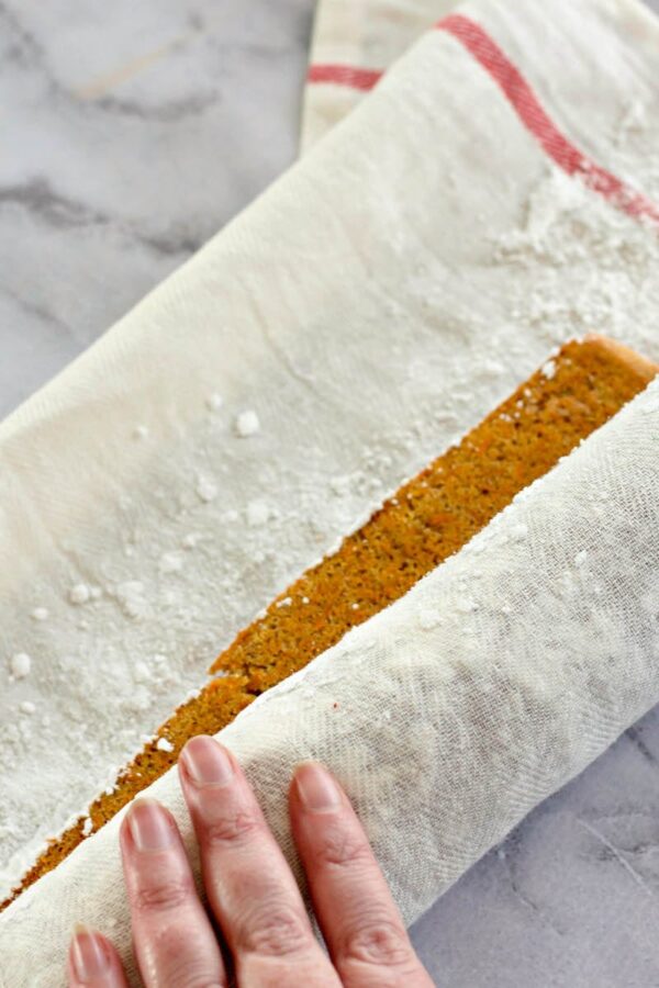 A warm carrot cake being rolled to cool.