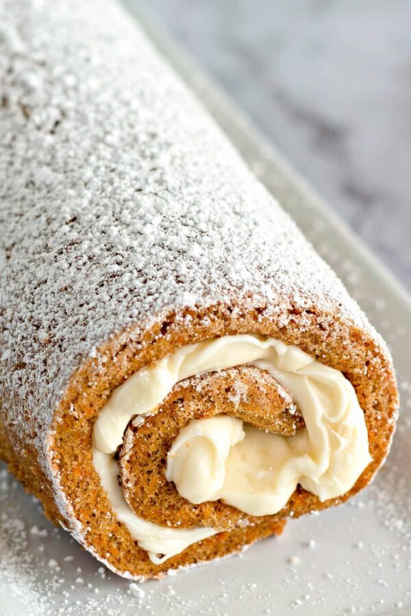A carrot cake roll freshly iced and rolled up. 