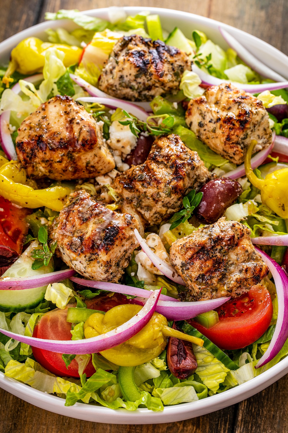 Chicken souvlaki on top of a salad.