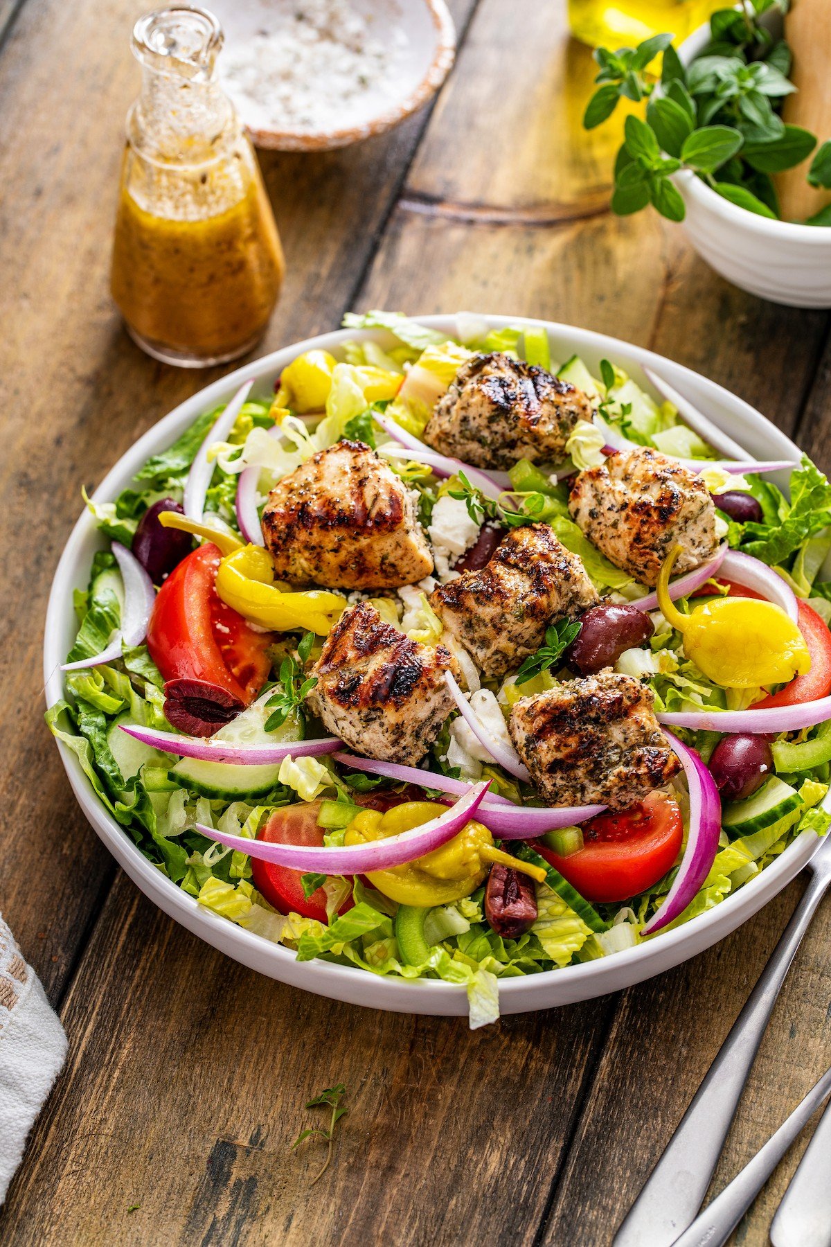 Big bowl of salad with feta cheese and Greek dressing on top.