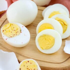 Hard boiled eggs peeled and halved on a wooden cutting board