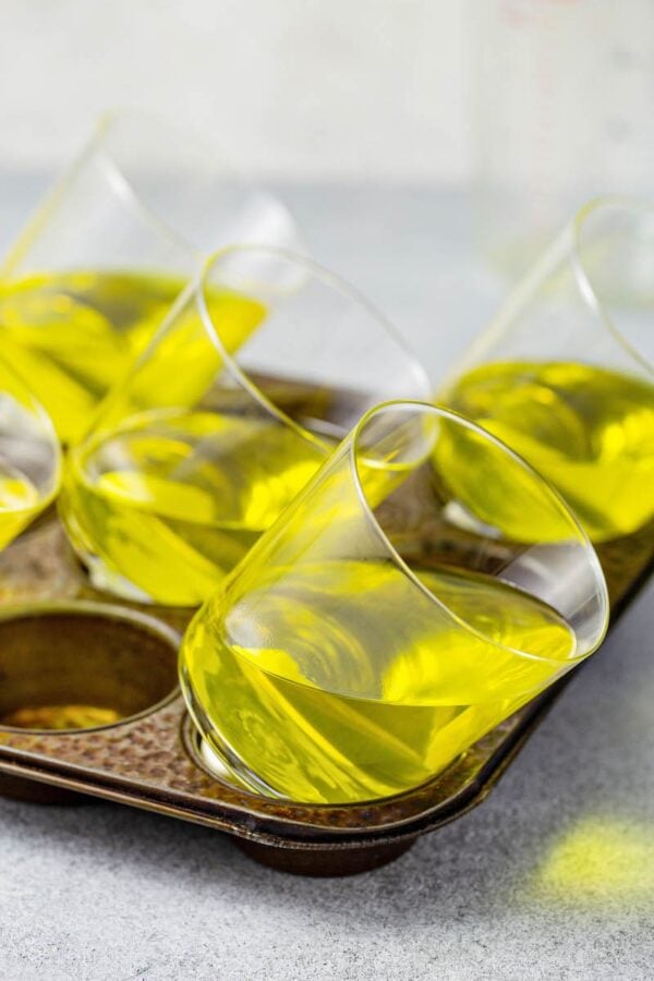 Cups with lemon jello inside in a muffin pan.