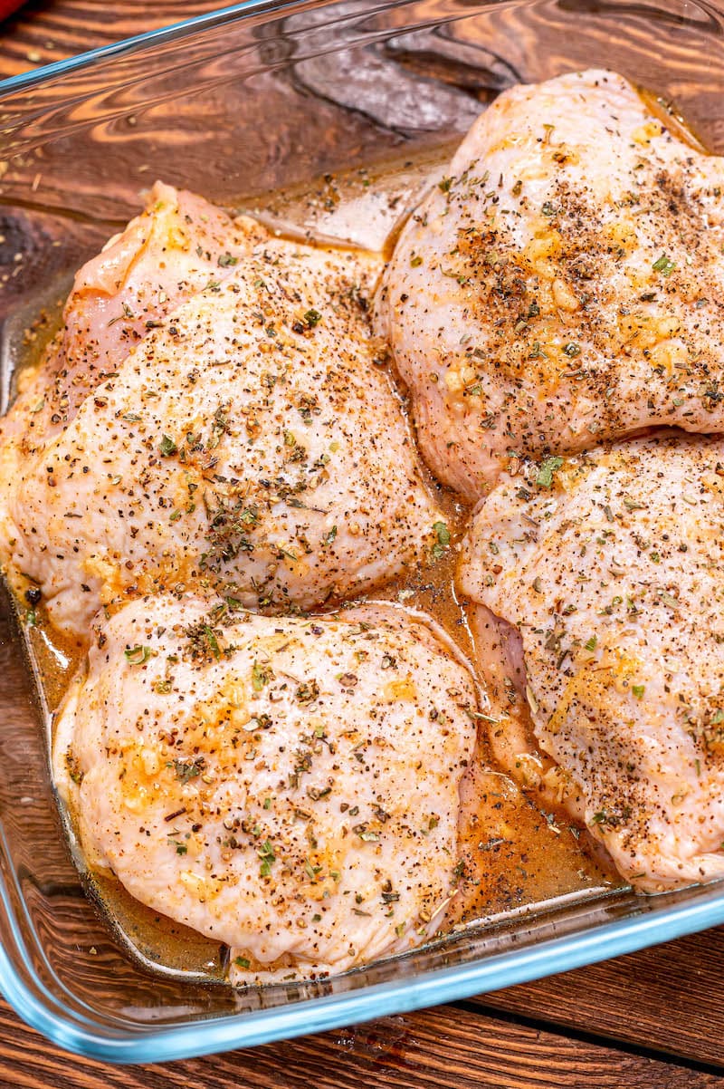 Raw bone-in skin on chicken breasts and thighs, seasoned and ready to be baked.