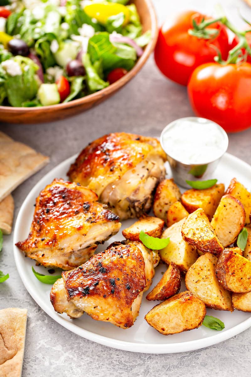Perfectly baked chicken on a white plate with roasted potatoes.
