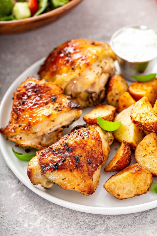 Perfectly baked chicken on a white plate with roasted potatoes.