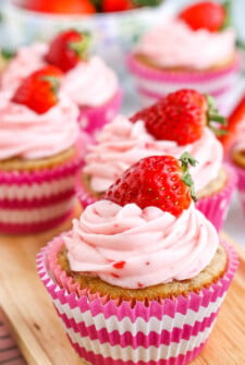 Close up image of 3 perfectly frosted strawberry cupcakes.