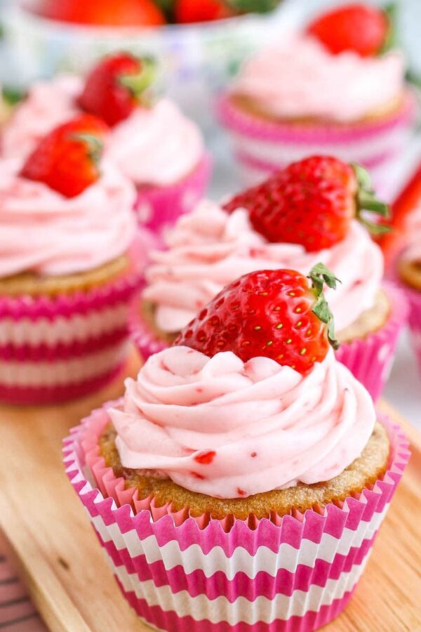 Close up image of 3 perfectly frosted strawberry cupcakes. 