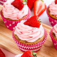 Close up image of 3 perfectly frosted strawberry cupcakes.