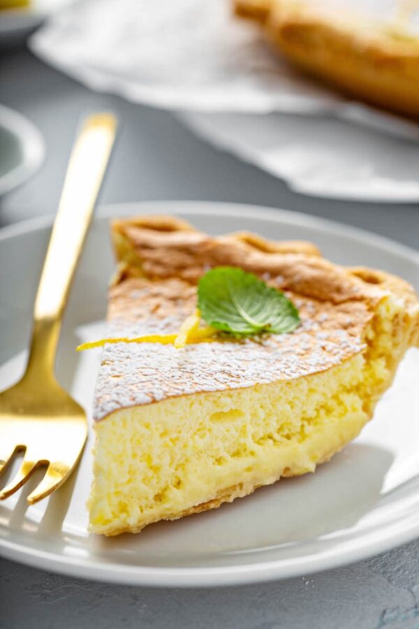 Slice of lemon pie on a white plate with a fork. 