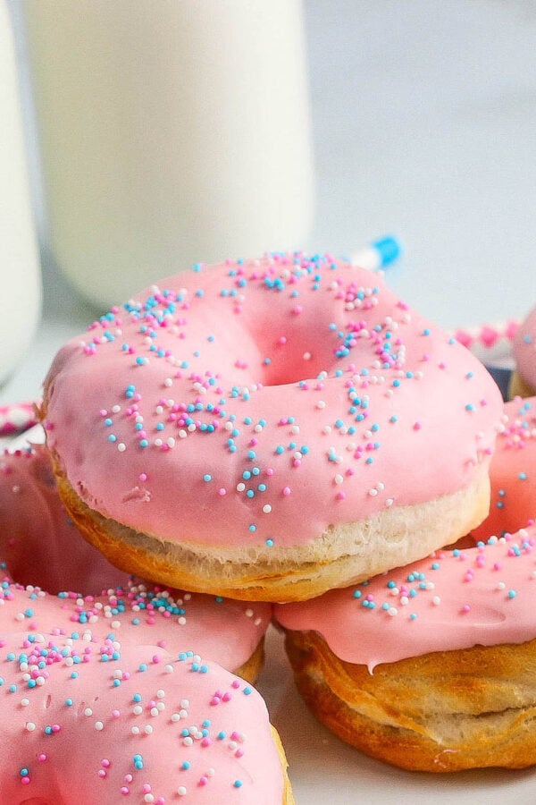 A stack of strawberry glazed donuts with pastel sprinkles.
