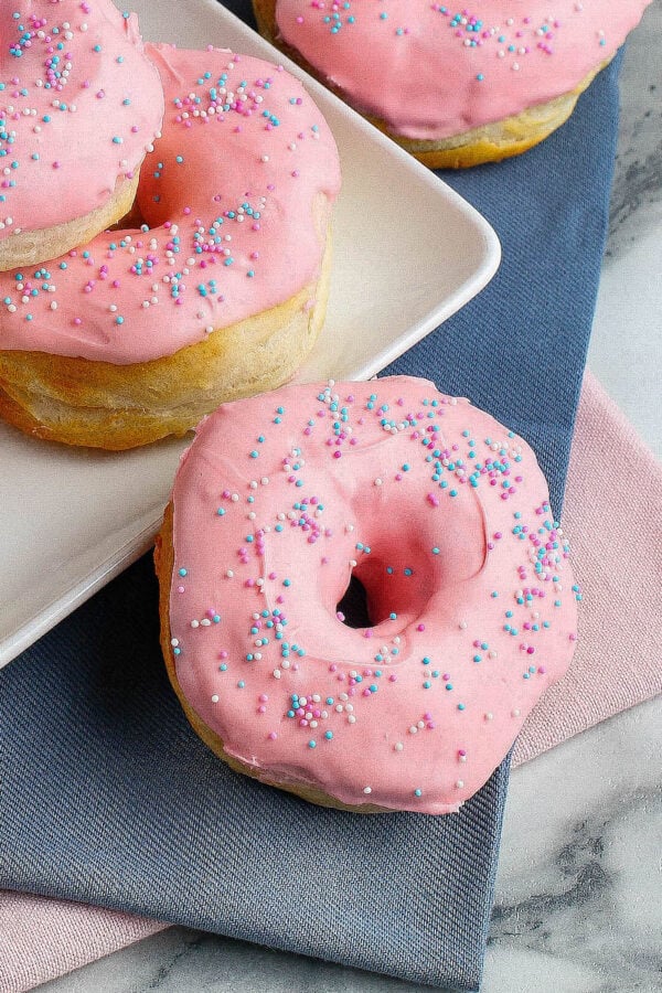 Strawberry glazed air fryer donuts topped with sprinkles.