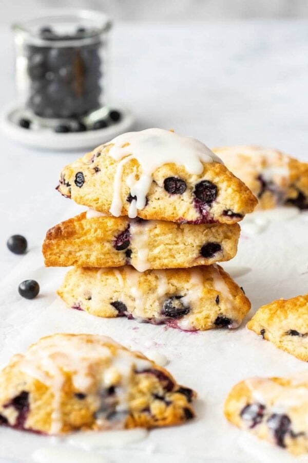 A stack of three blueberry scones drizzled with vanilla glaze.