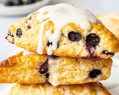 A stack of three blueberry scones drizzled with vanilla glaze