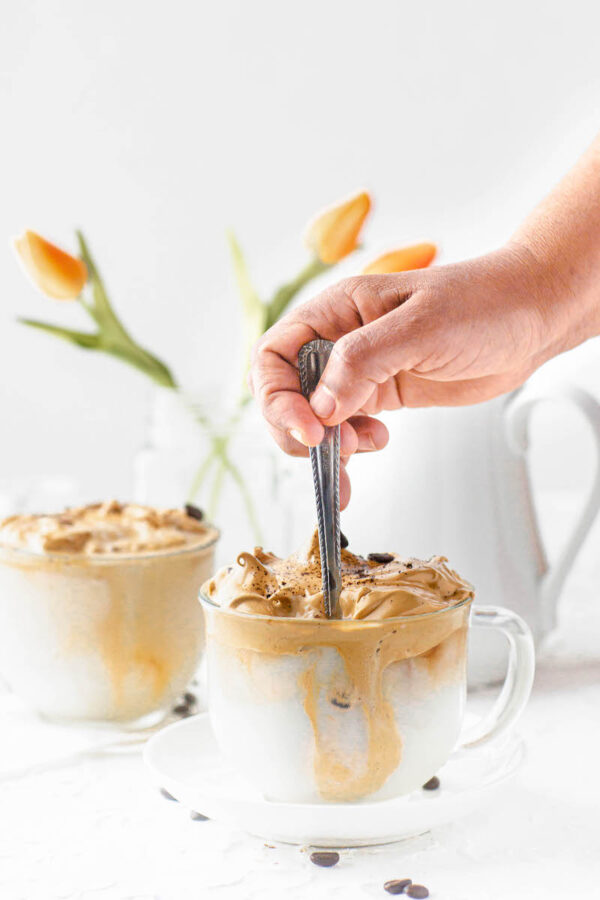 Whipped coffee being stirred with a spoon. 