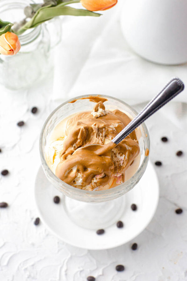 Whipped coffee served on top of ice cream in a glass bowl with a spoon.
