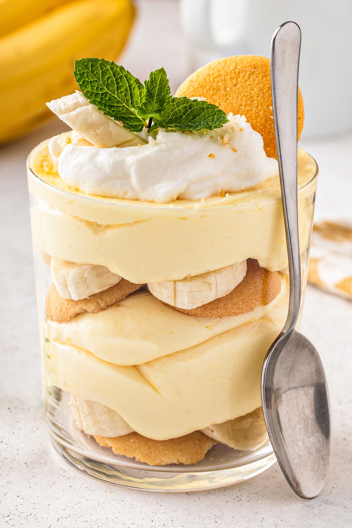A personal sized banana pudding with a spoon leaning against it