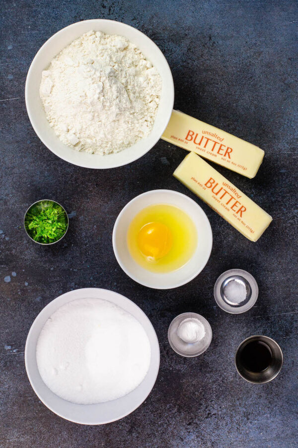 Ingredients in bowls for key lime cookies on a dark background. 