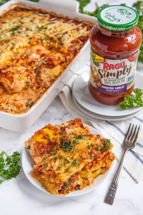 Ravioli lasagna on a plate and in a casserole dish with a fork and marinara sauce in a jar.