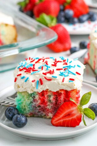 4th of July Cake on a white plate with sprinkles and fresh fruit.