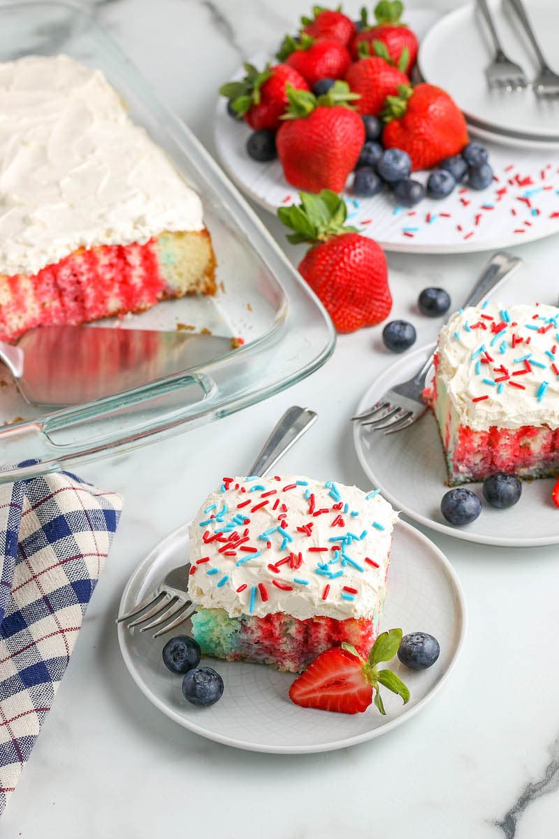 4th of July Cake on plates and in a baking pan with forks and fresh fruit. 