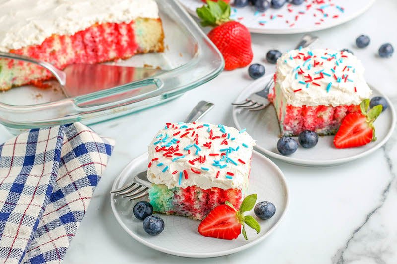 4th of July Cake slices on plates with fresh fruit.