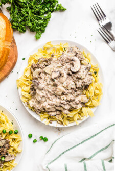 Beef Stroganoff on a white plate with a fork and a napkin.