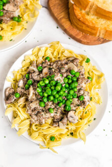Beef Stroganoff on a plate topped with green peas.