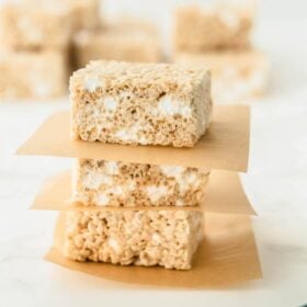 Three rice krispies treats stacked on top of each other with parchment paper.