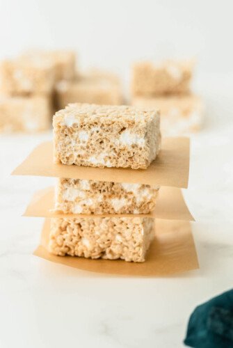 Three rice krispies treats stacked on top of each other with parchment paper.