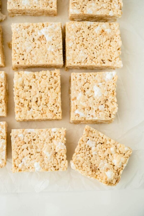Krispie bars are sliced in squares on parchment paper.