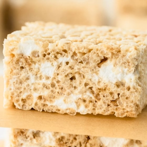 Cereal bars are stacked and separated with squares of brown parchment paper.