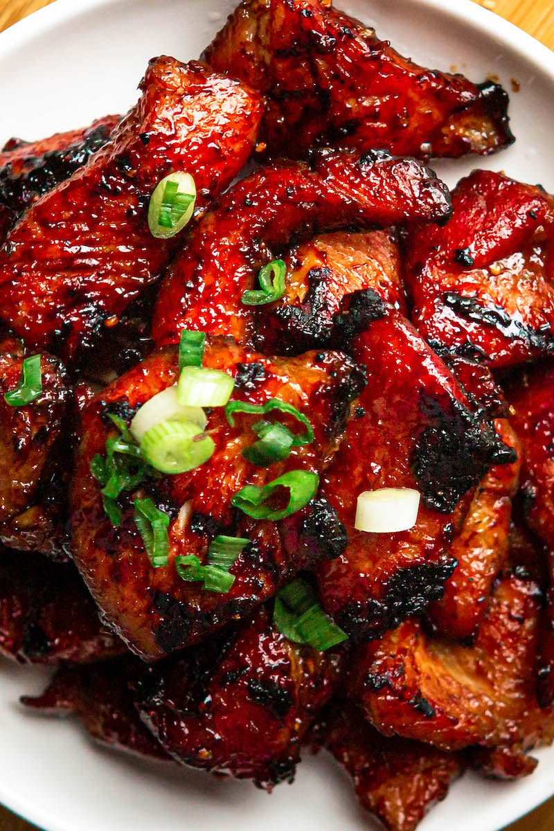 Char Siu on a plate with green onions on top.