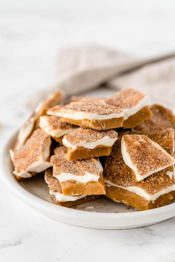 Cinnamon sugar toffee stacked on top of each other on a white plate.