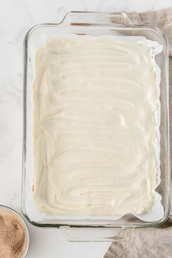 Toffee with white chocolate spread on top in a glass baking dish.