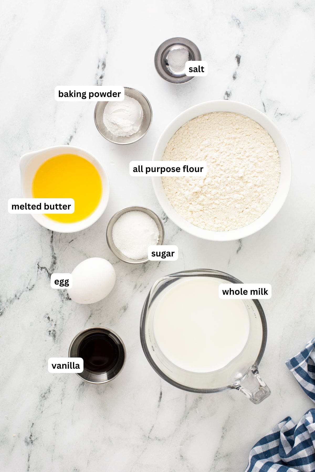 Ingredients for fluffy pancake recipe in order from top to bottom: salt, baking powder, all purpose flour, melted butter, sugar, egg, vanilla, whole milk.